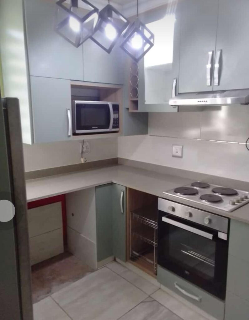 Fitted kitchen with sage cabinetry, built-in oven and stone worktop