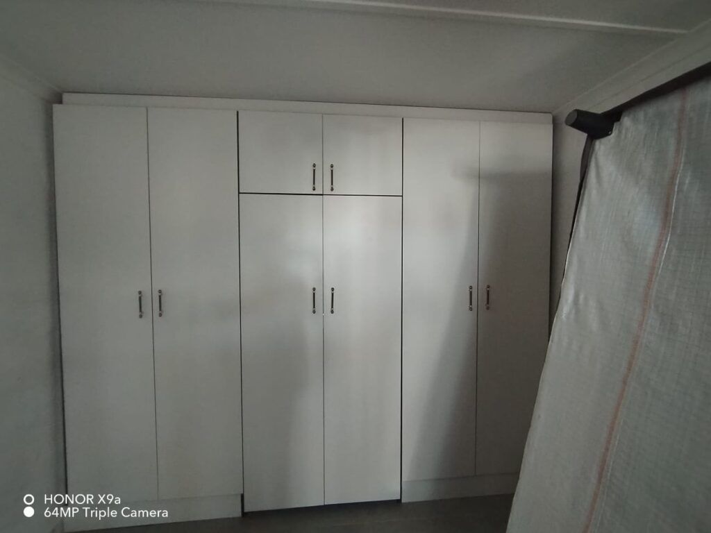 White built-in bedroom cupboards with overhead bulkhead storage