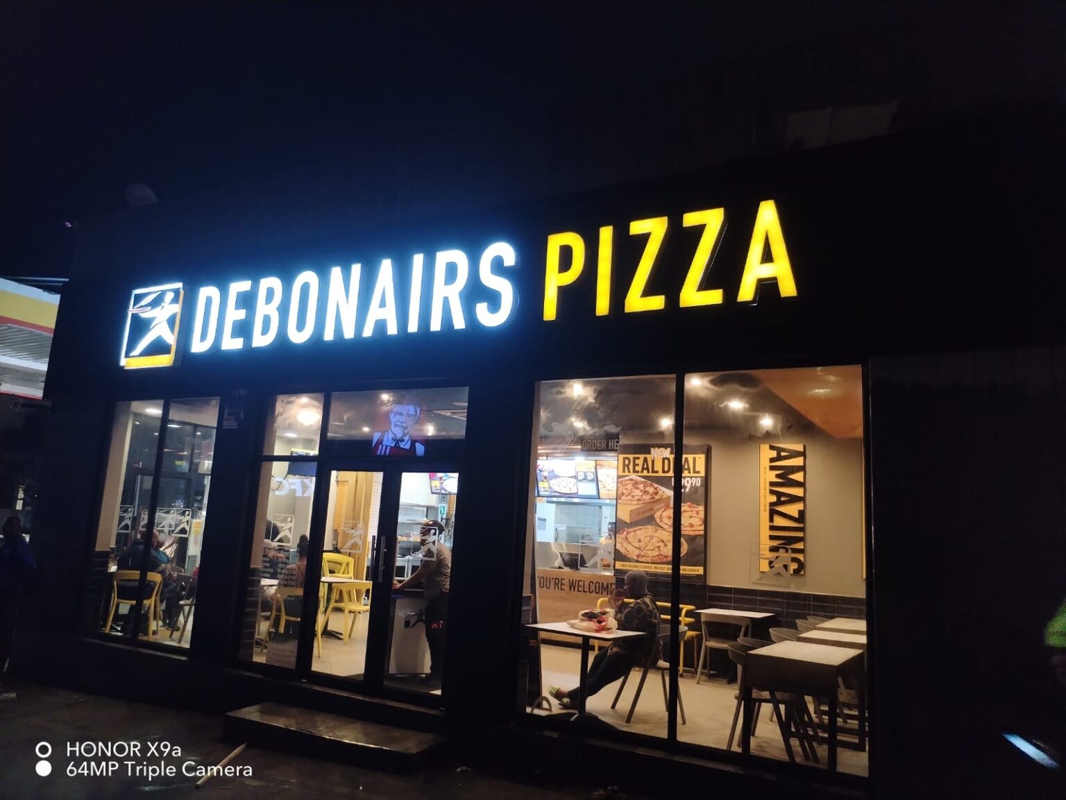 Illuminated retail shopfront with glass frontage and fitted seating inside