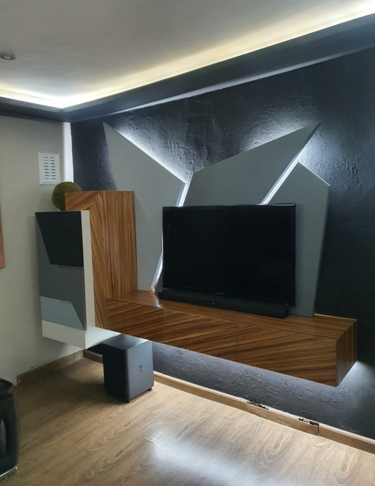 Bold geometry, warm timber, and dramatic lighting come together to create a striking modern entertainment space.